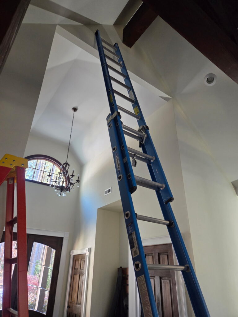 Commercial interior painting in Melbourne, FL showing ladder setup for high walls and precise painting prep by Fresh Finish Custom Coatings.